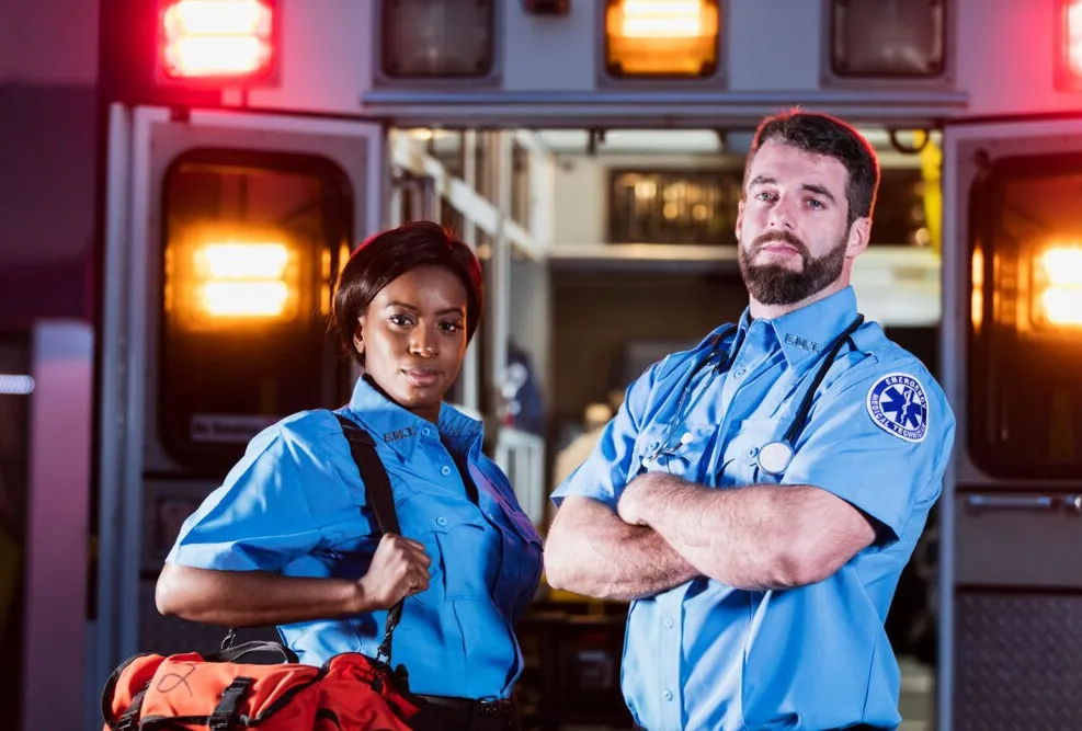 A pair of EMTs in front of an ambulance.